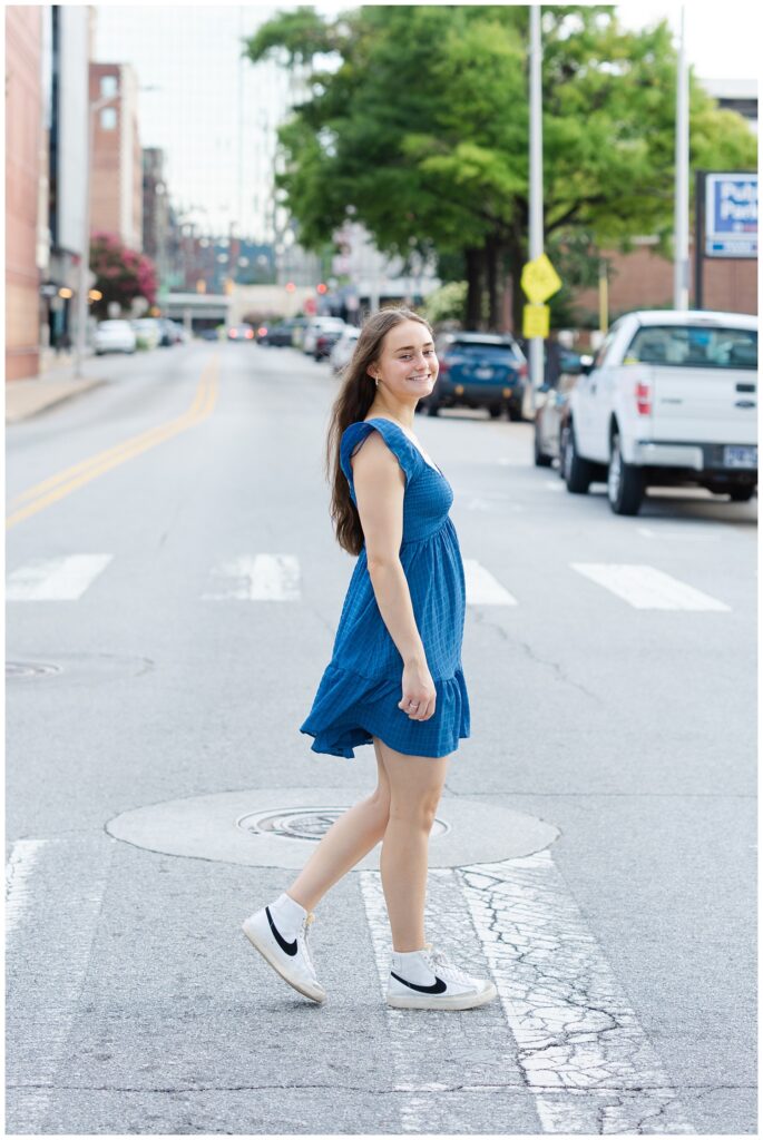 senior girl wearing a blue dress and walking within the crosswalk in Chattanooga 