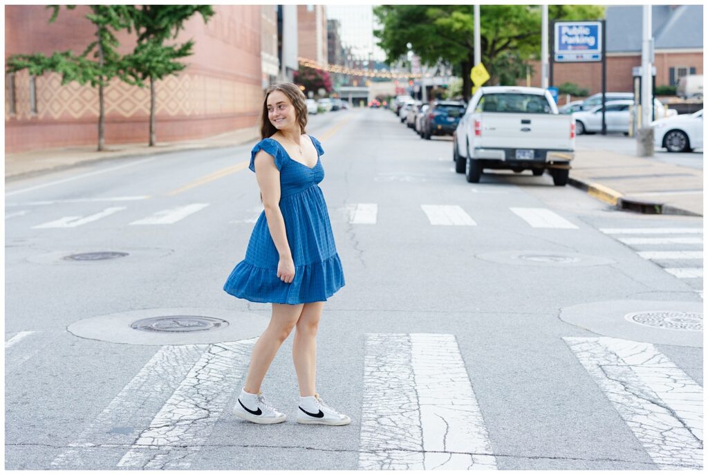 senior girl wearing a blue dress and walking within the crosswalk in Chattanooga 