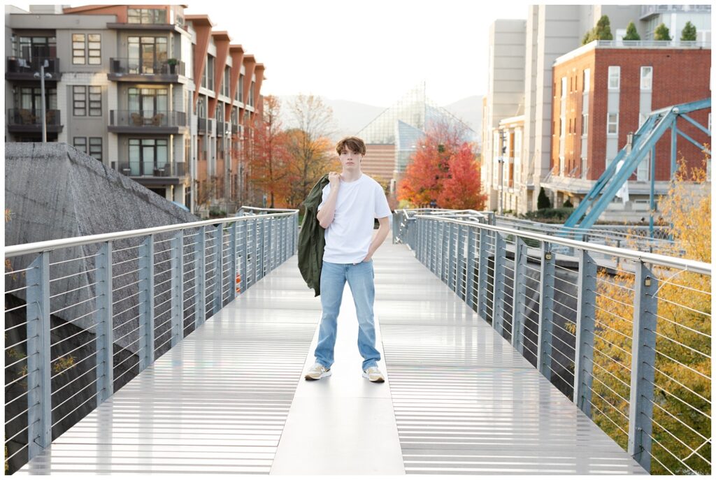 senior holding his green jacket over his shoulder on the steel walking bridge
