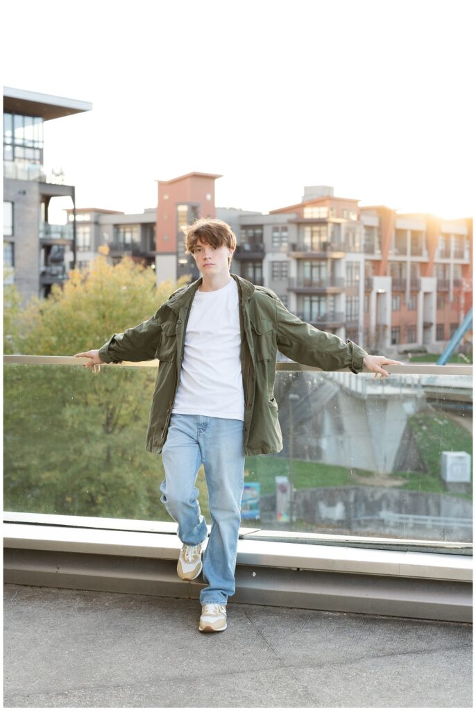 high school senior guy leaning against the glass wall near the Hunter Museum