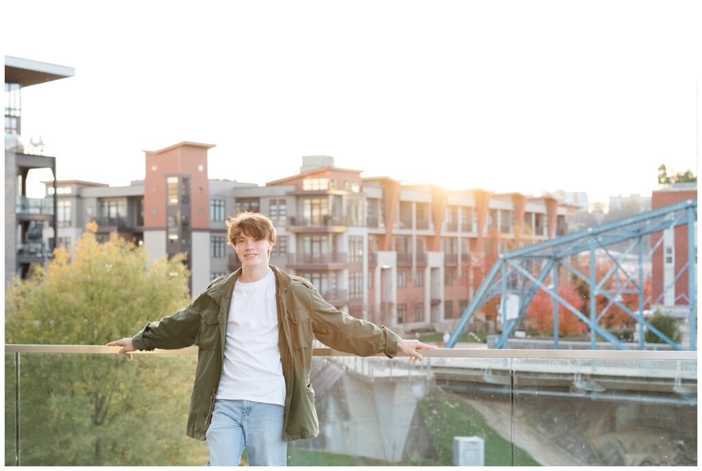 high school senior guy smiling and leaning against the glass wall near the Hunter Museum in Chattanooga