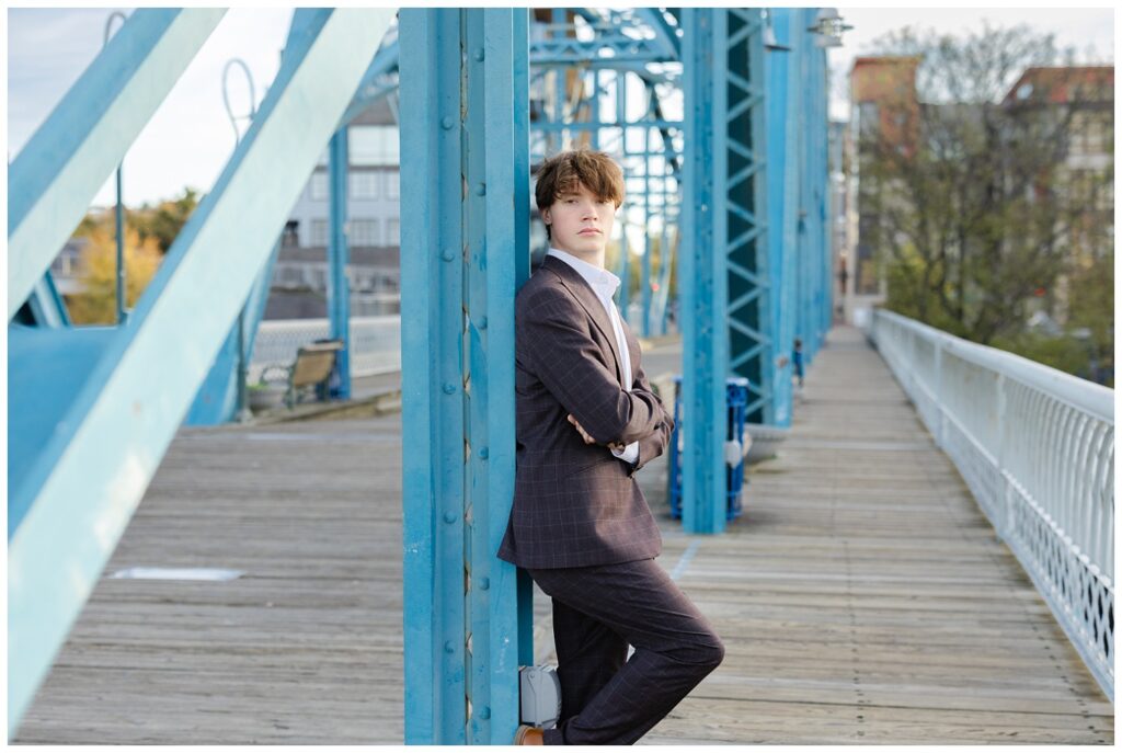 senior leaning against the blue girder of the Walnut Street Bridge for Chattanooga session