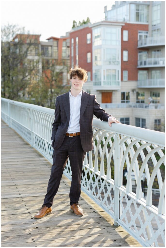 senior guy wearing a blue striped suit and posing against the railing of the Walnut Street Bridge