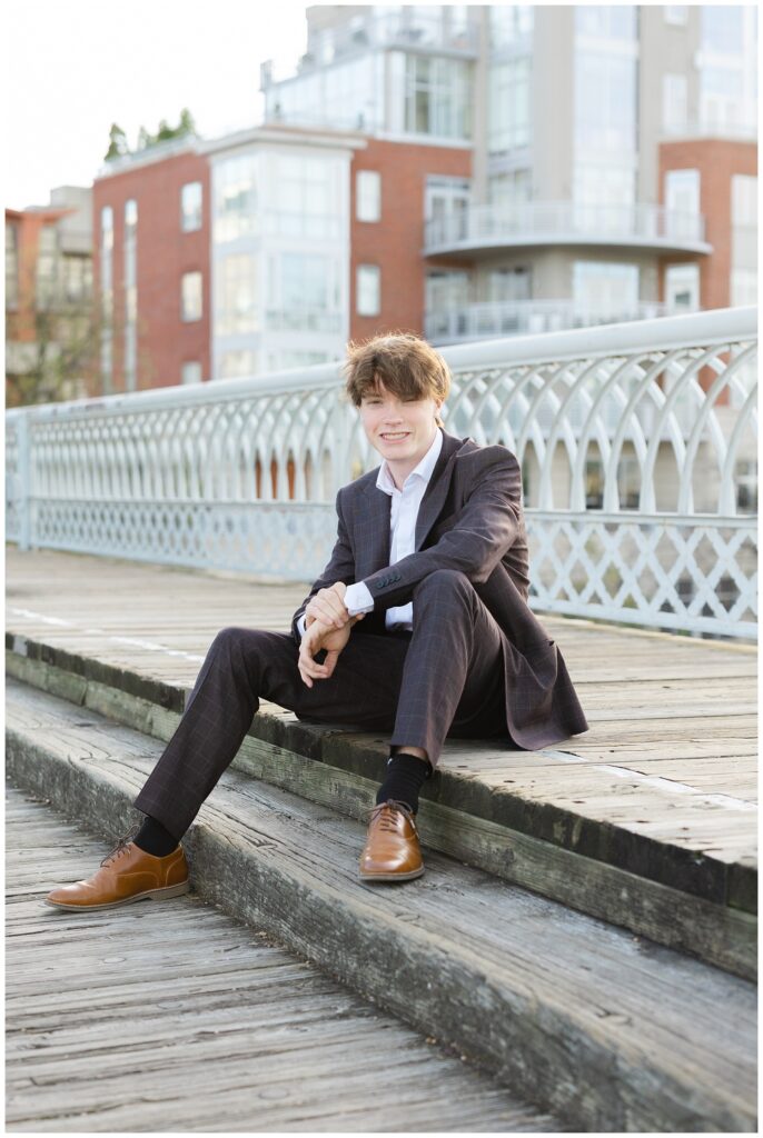 senior boy sitting on the wooden sidewalk on the Walnut Street Bridge in Chattanooga