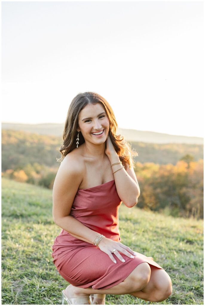 senior girl kneeling down on the grass and laughing for photoshoot on Raccoon Mountain