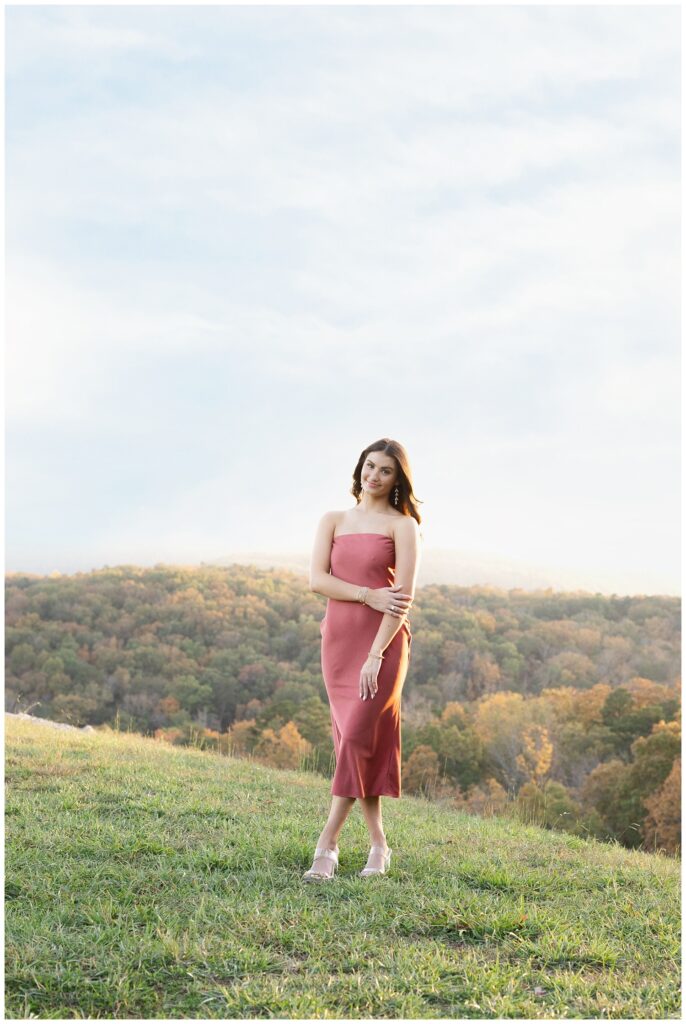 senior girl holding her forearm and smiling among the trees and mountains in Chattanooga