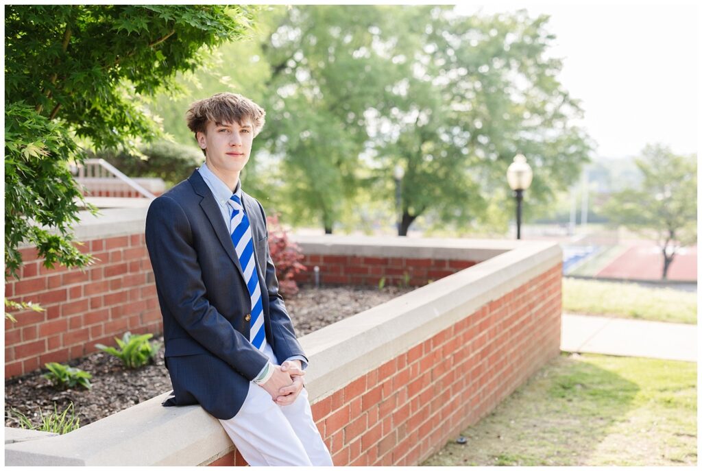 high school senior sitting on a stone and brick wall for spring portraits in Chattanooga