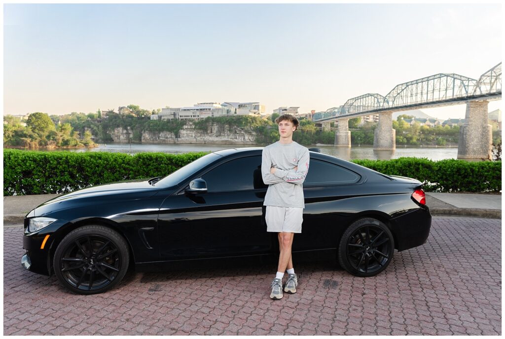 senior guy leaning against his black BMW in Renaissance Park in downtown Chattanooga