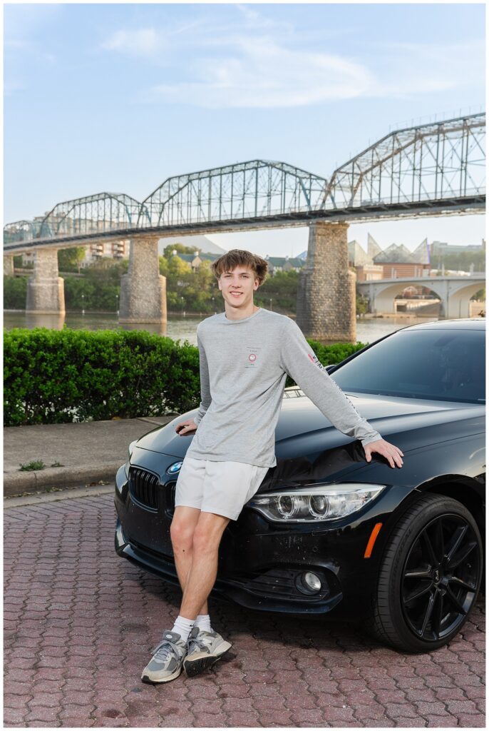 senior boy leaning against his black two door BMW in Renaissance Park for spring session