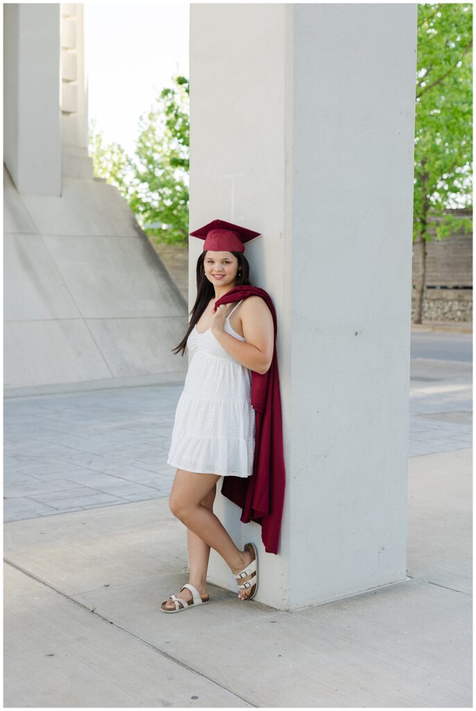 high school senior girl leaning against a concrete column near Coolidge Park