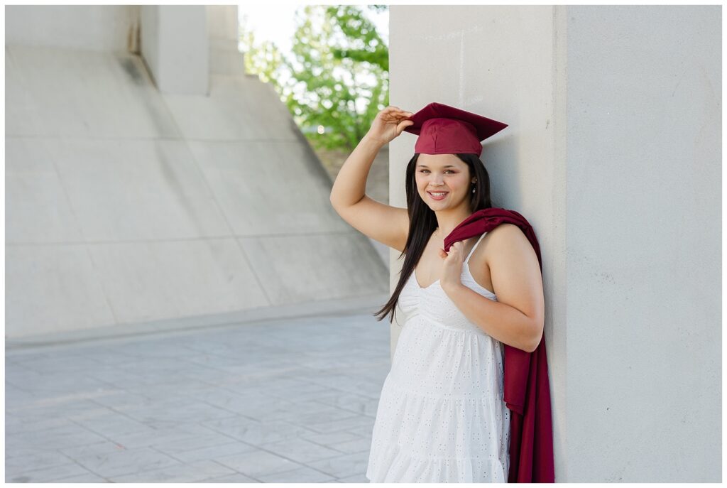 high school senior girl leaning against a concrete column near Renaissance Park