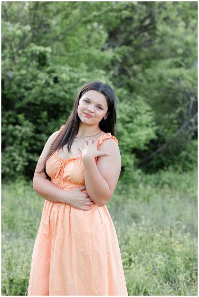 senior girl holding her arm on her shoulder while standing in a Chattanooga field
