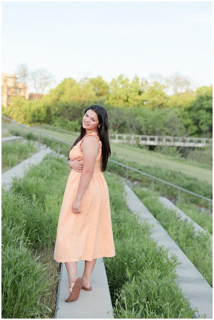senior girl standing on a concrete bench around grass in Renaissance Park