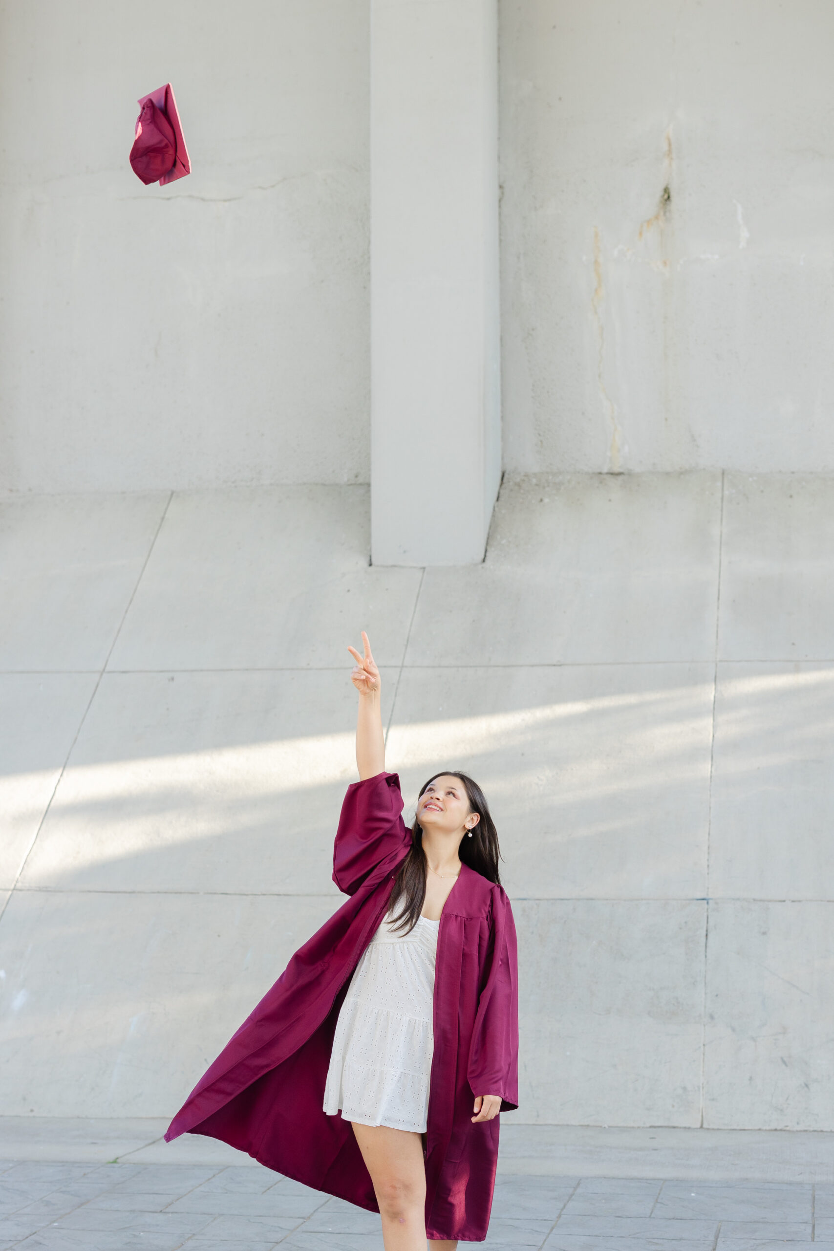 senior girl throwing her graduation cap in the air at Renaissance Park