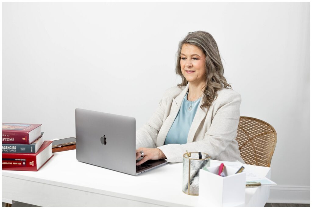nurse practitioner writing in her laptop at a white desk at studio for Chattanooga branding session