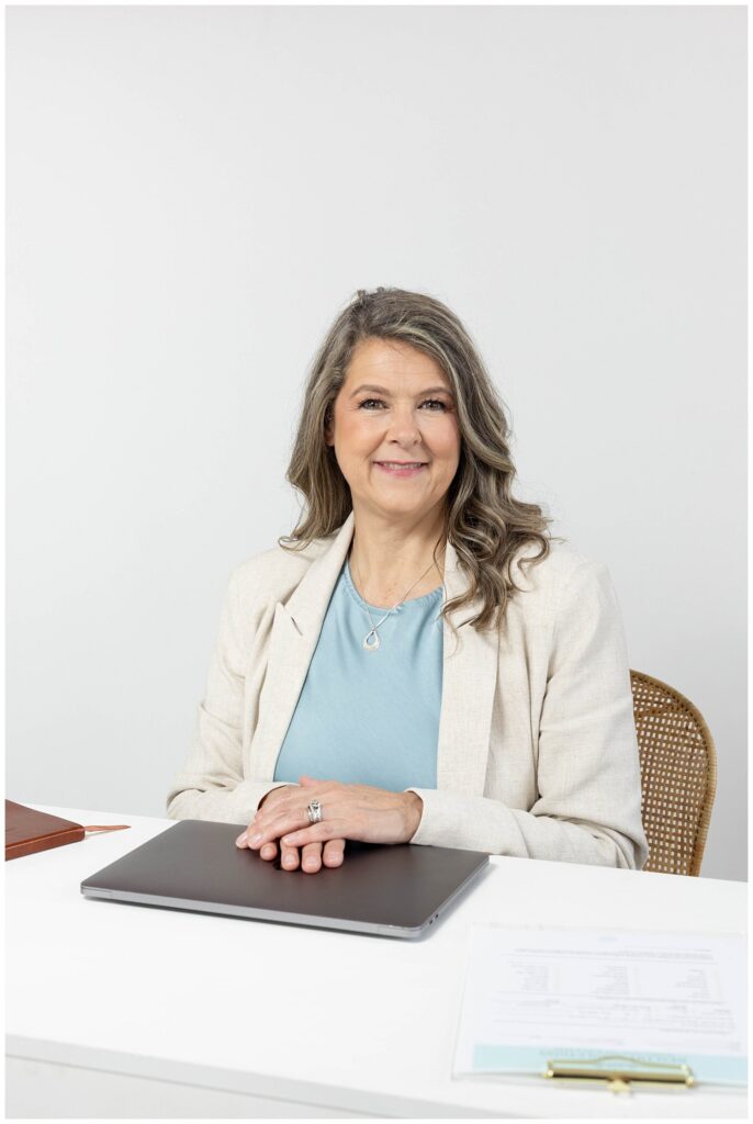 Chattanooga nurse practitioner sitting at a desk with hands on laptop for branding photoshoot