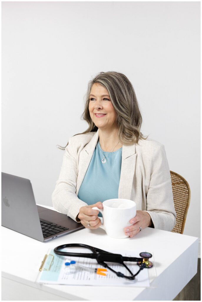 nurse wearing a blue blouse and beige linen suit holding a white coffee cup at branding session