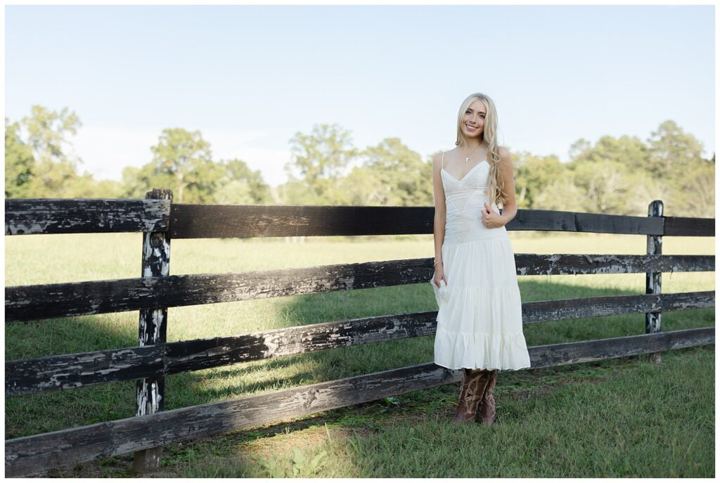 high school senior posing at a fence on her family farm in Chattanooga wearing cowboy boots