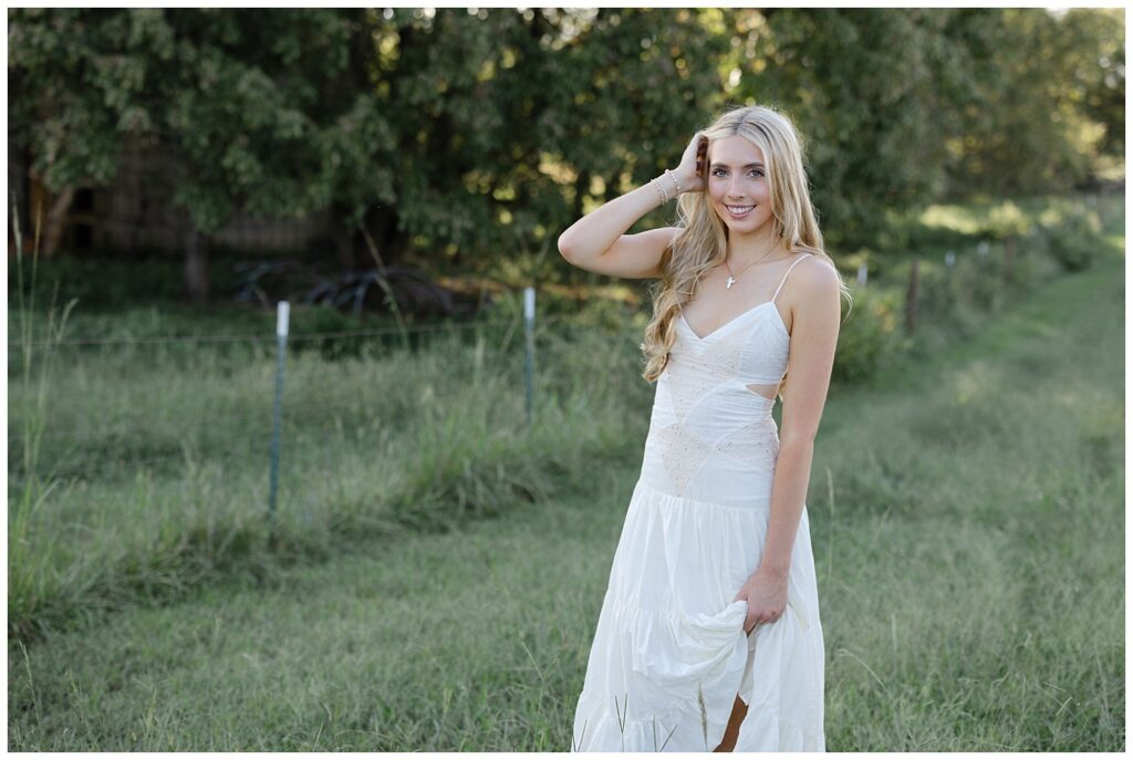 Chattanooga high school senior smiling, wearing a white dress and holding her hand in her hair