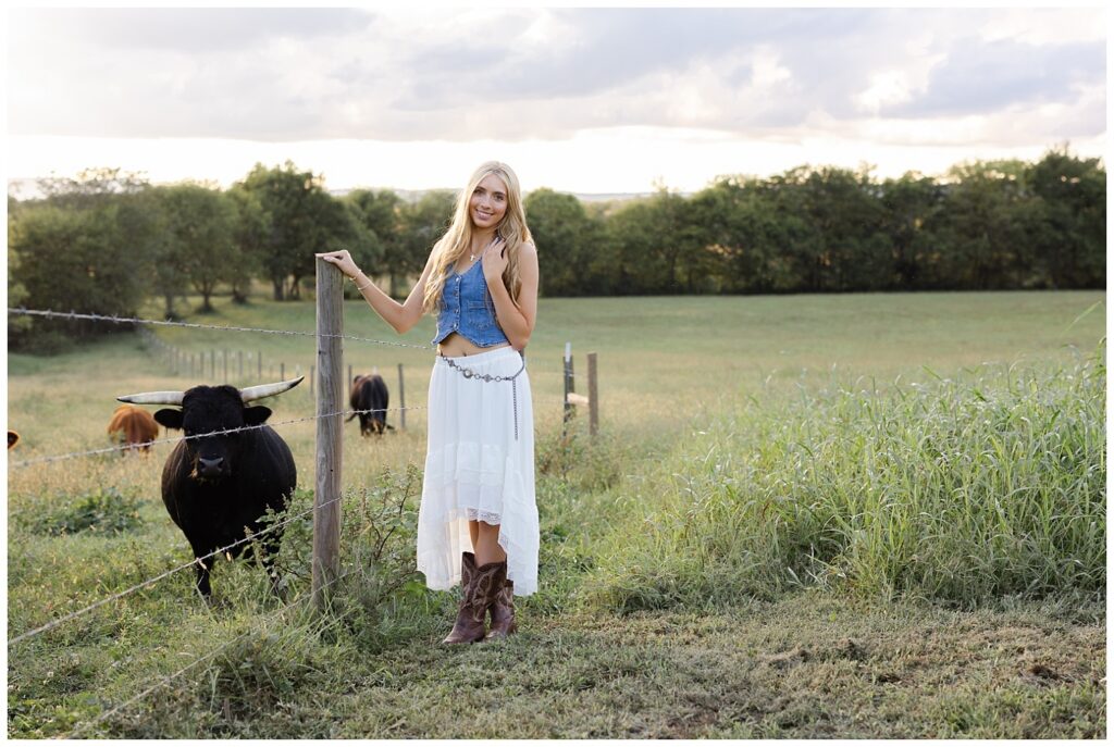 high school senior girl posing next to cows on her family farm near Chattanooga