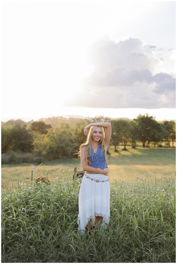 senior girl resting her arm on her head while posing in her family's field for Chattanooga photoshoot