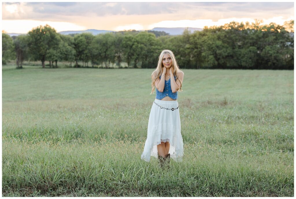 north Georgia high school senior holding her hands around her neck and standing on her family farm