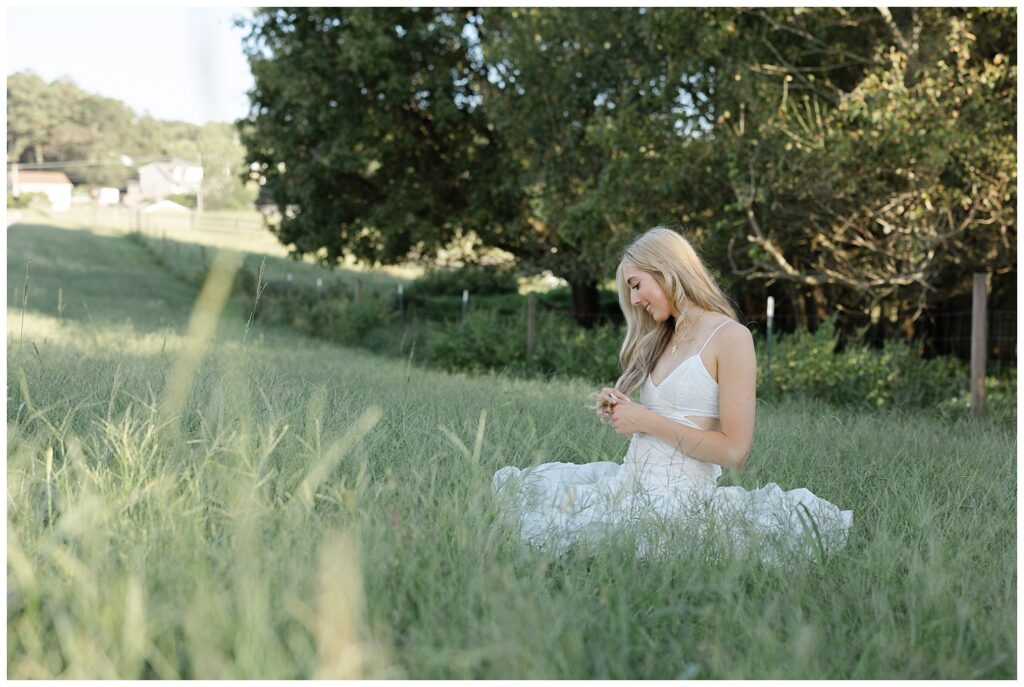 senior leaning back and sitting in the grass of her family farm in north Georgia near Chattanooga