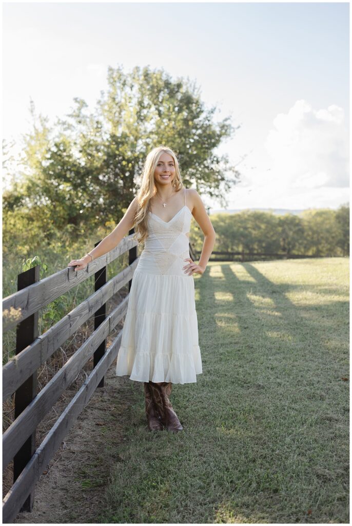 Chattanooga high school senior holding onto the fence on her family farm for photoshoot
