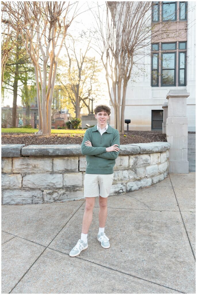senior guy crossing his arms and posing in front of a stone wall at Chattanooga courthouse