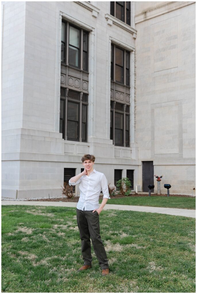 high school senior posing with his hand on his neck with the Chattanooga courthouse in the background